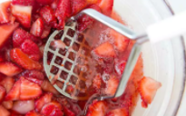 Mashing strawberries to create jam